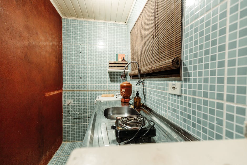 A cozy kitchenette with blue tiles, sink, and a single electric burner.