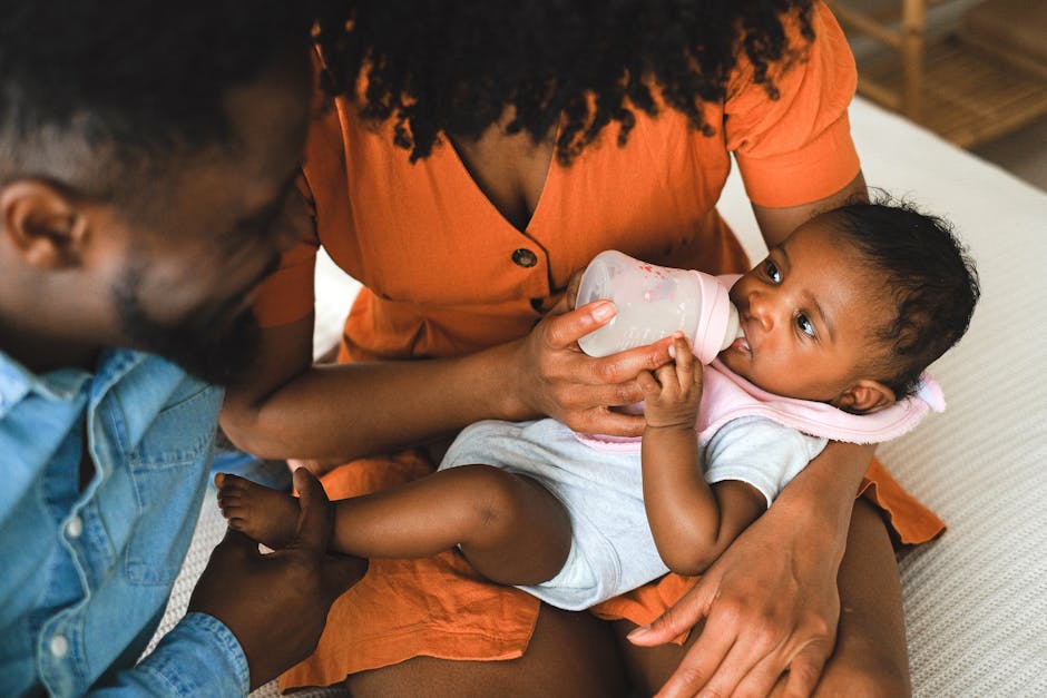 Parents lovingly feeding their baby with a bottle. A warm family moment captured indoors.